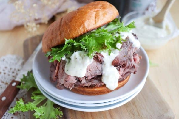 A sandwich made with toasted buns, roast beef, lettuce, and garlic aioli. 