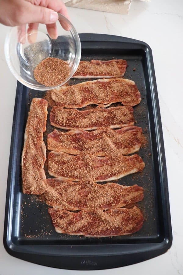 The dry rub recipe is being sprinkled on top of short ribs.
