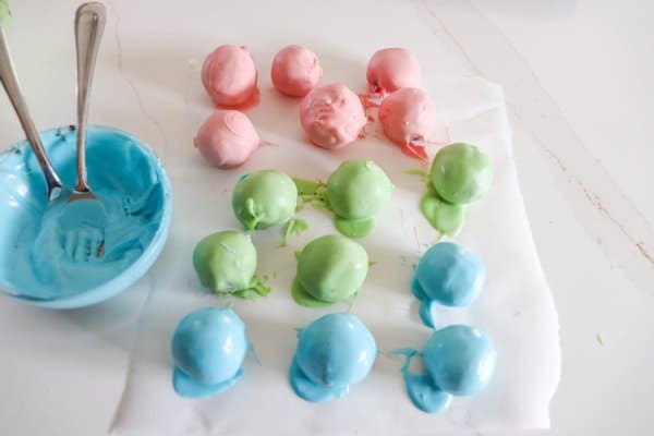 Oreo cake balls in pastel colors on a piece of parchment paper.