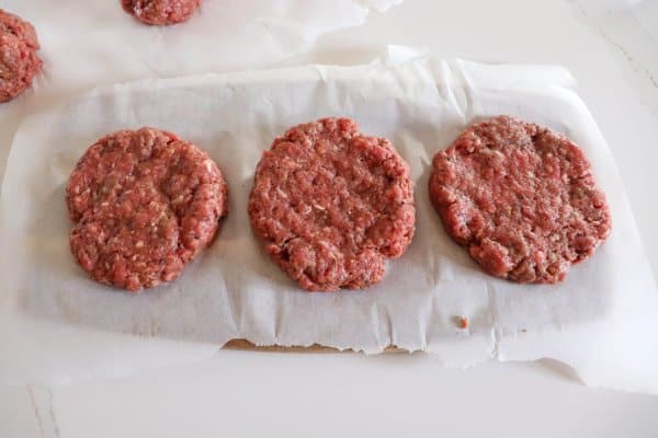 Raw burger patties for smoking on a sheet of parchment paper.