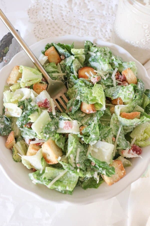 A classic Caesar salad in a white bowl with a fork.