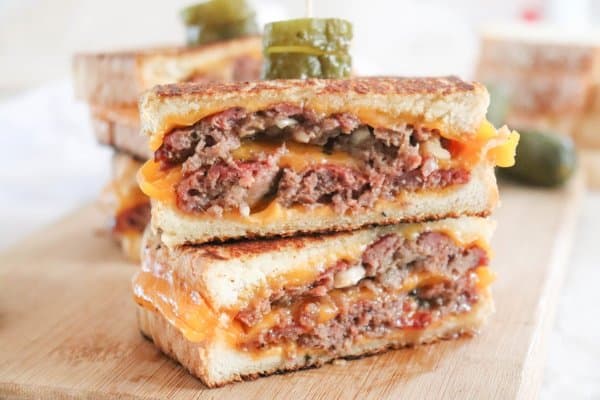 Grilled Cheese Burgers with golden brown toasted bread on a cutting board.