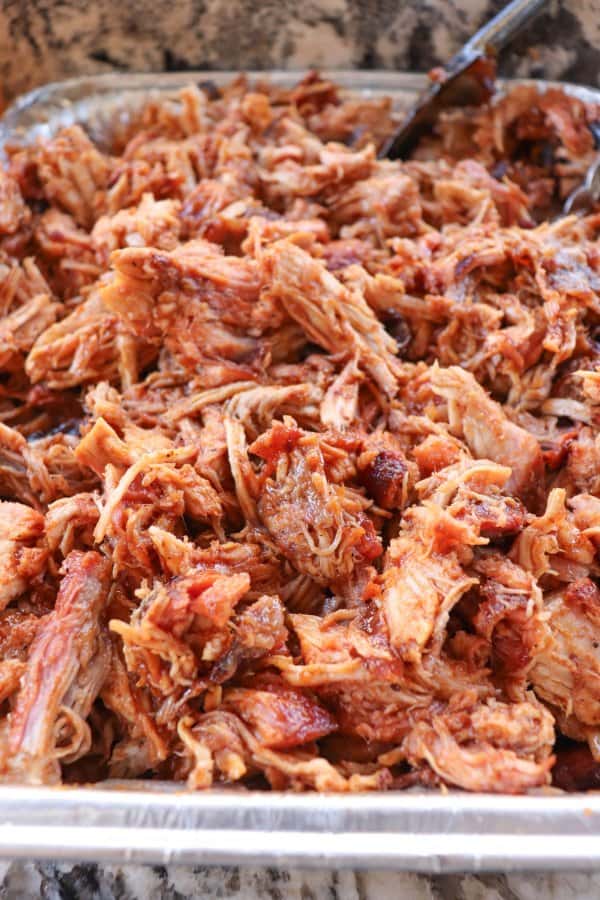 Smoked Pulled Pork close up in an aluminum tray covered in bbq sauce.