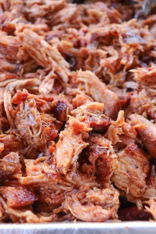 Smoked Pulled Pork close up in an aluminum tray covered in bbq sauce.
