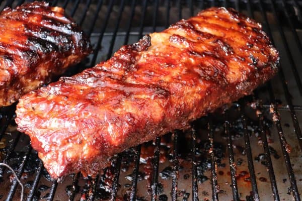 Smoked pulled pork loin with bbq sauce on a grill.