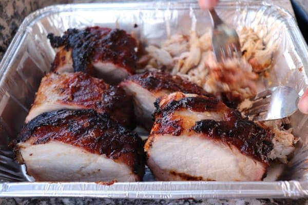 Chunks of cooked pork loin in an aluminum tray.