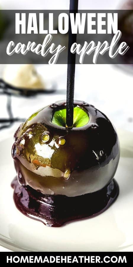 Black Halloween candy apple on a white plate with a black stick.