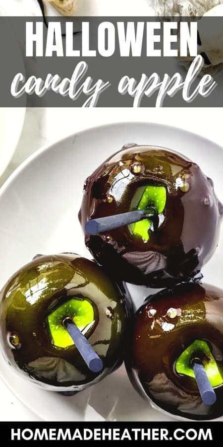 Three black Halloween candy apples on a white plate.