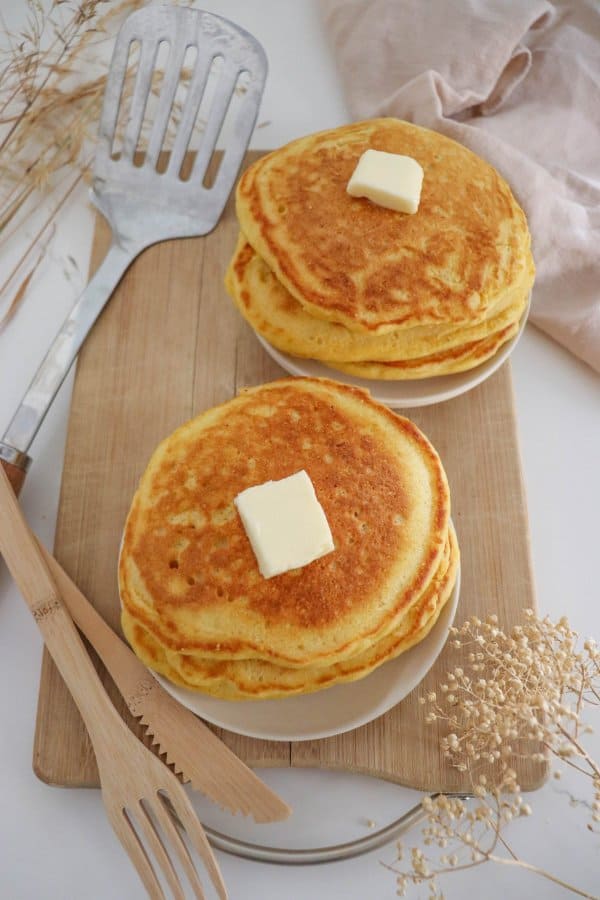 Two plates of pancakes made with the cornmeal pancake recipe.