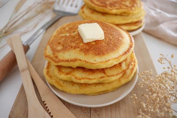 A stack of cornmeal pancakes with a pat of butter on top.