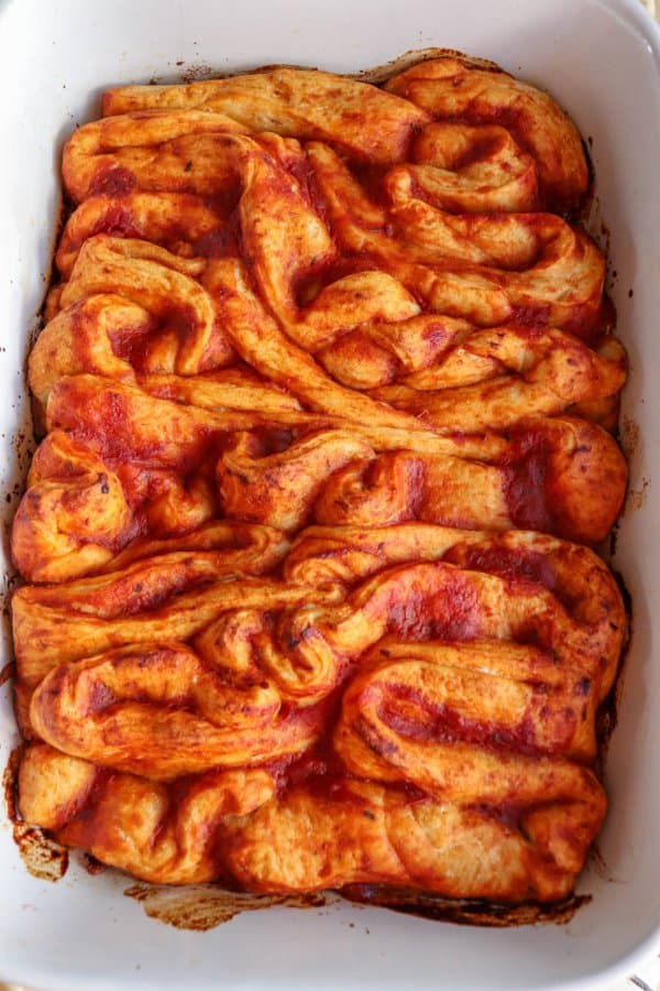 Pizza in the shape of intestines in a white casserole dish.