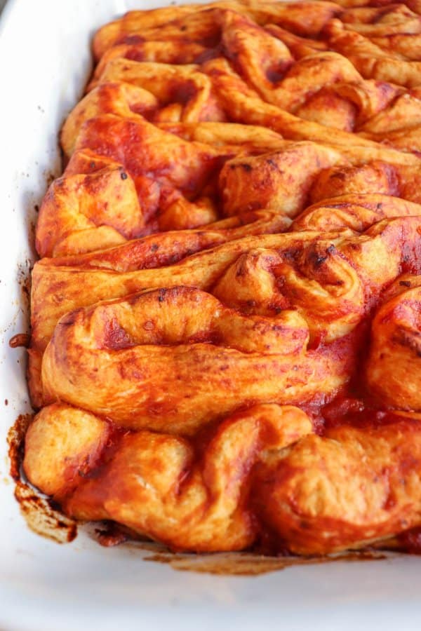 Pizza in the shape of intestines in a white casserole dish.