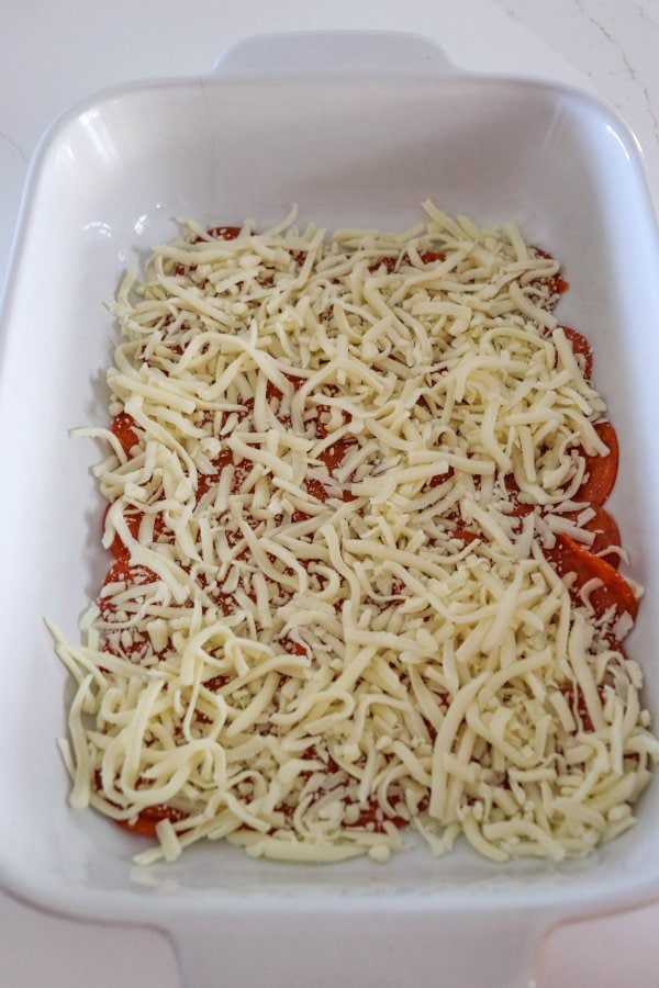 Halloween Deep Dish Pizza Process with pepperoni and mozza cheese in a white casserole dish.