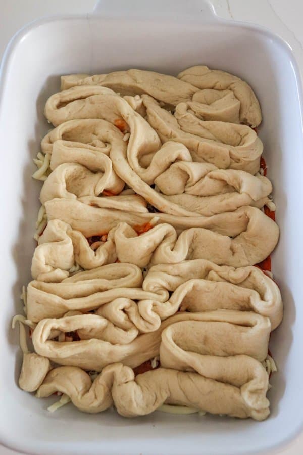 Halloween Intestine Pizza Dough Process of shaping dough in a white casserole dish.