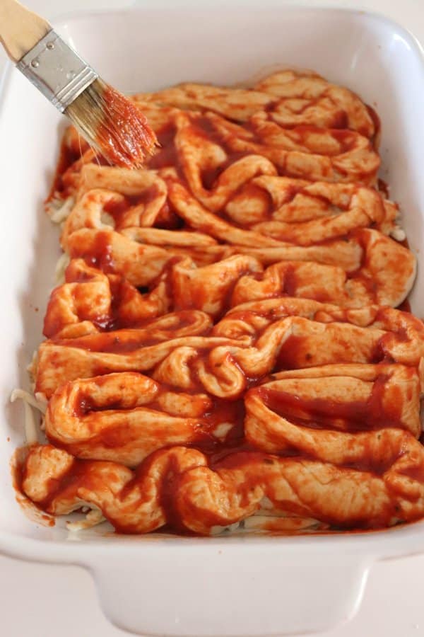 Pizza in the shape of intestines in a white casserole dish.