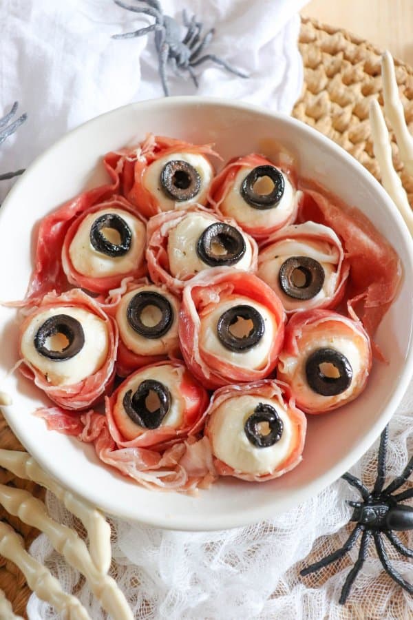 Mozza balls wrapped in prosciutto with sliced black olives made to look like eyeballs.