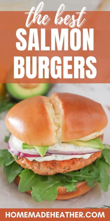 Salmon burger topped with creamy dill sauce, red onion and avocado on a bed of lettuce in a white bun with text overlay.
