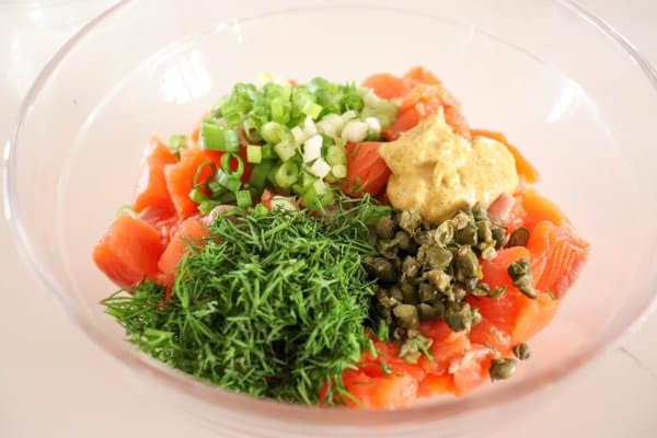 Salmon burger ingredients in a bowl on a white counter.