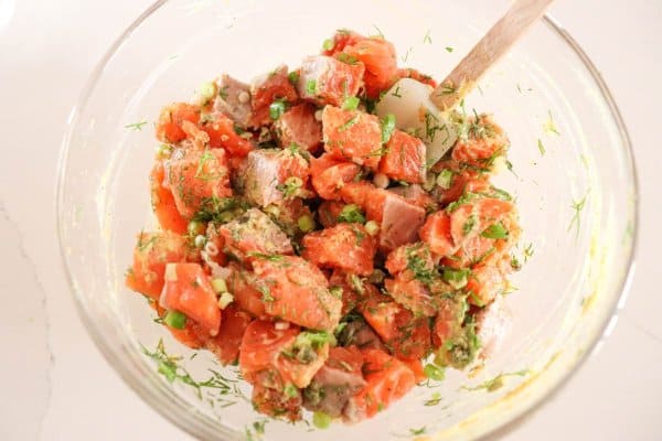 Salmon burger ingredients mixed in a glass bowl.