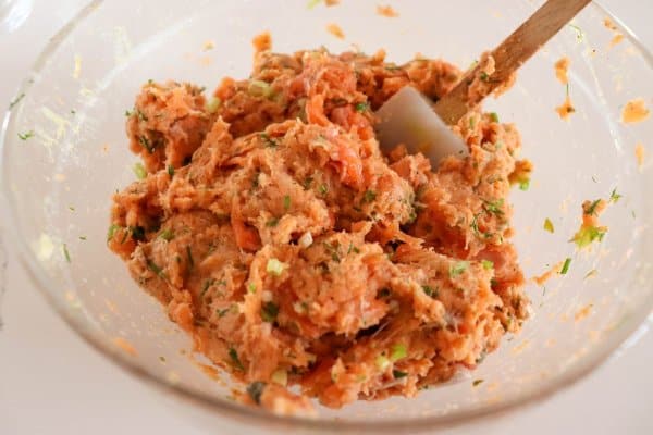 Salmon burger mixture processed in a clear glass bowl.