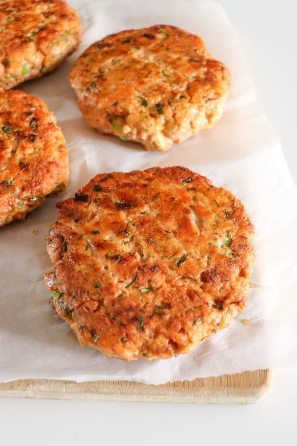 Cooked salmon burger patties on parchment paper.