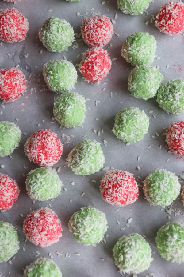 Red and green coconut-covered balls reminiscent of the delightful thin mint cookie recipe, arranged on a parchment-lined surface.