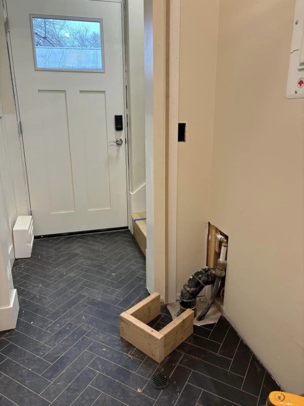 Ikea cabinet is used to hide the exposed plumbing with this mudroom hack.