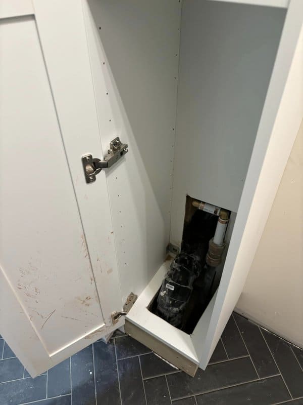 Covering exposed plumbing with an Ikea cabinet mudroom hack.