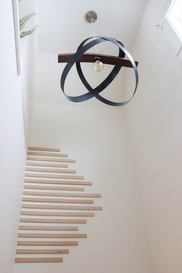 Wood trim pieces are laid horizontally to create a accent wall in a stairwell.
