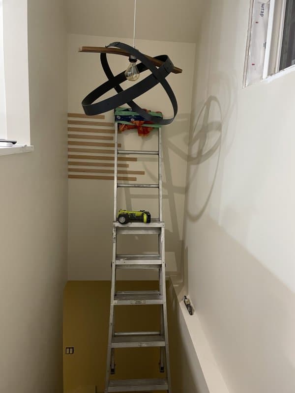 A ladder is used in the stairwell to add the trim to the wall.