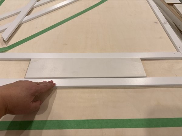 A block of wood is used to space the trim pieces evenly.