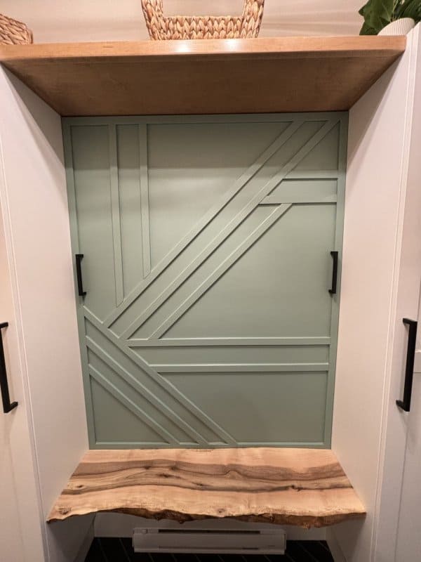 Finished geometric trim art above a mudroom bench.