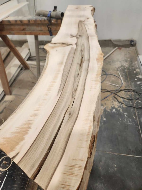 A live edge bench is being sanded.