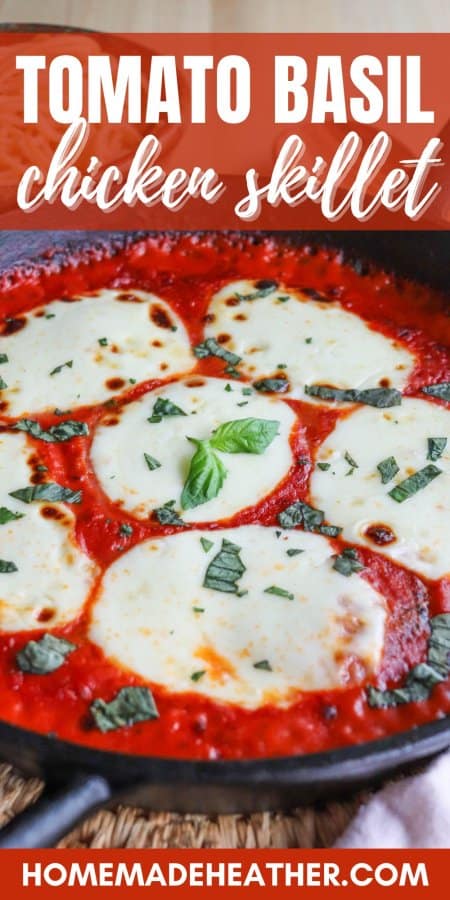 Mozzarella cheese rounds in a bed of tomato sauce covering chicken in a cast iron skillet topped with fresh chopped basil.
