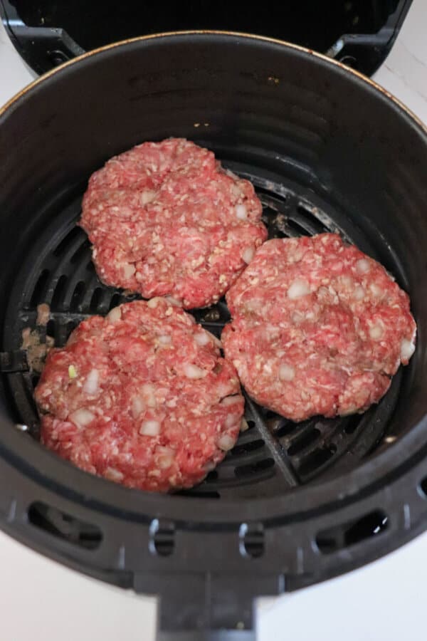 Burger patties in the air fryer basket.
