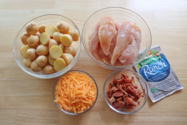 Ingredients for chicken bacon ranch foil packs in clear bowls on a wood background.
