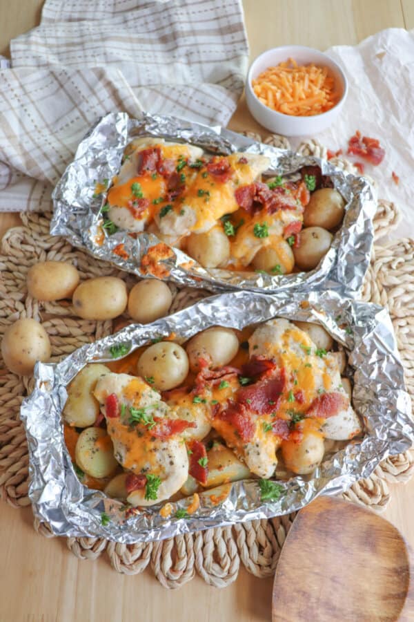 Chicken and baby potatoes covered in ranch seasoning, bacon bits and melted cheese in a foil packet.
