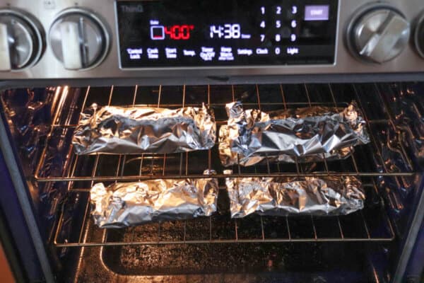 Four foil packets on the wire rack in the oven.