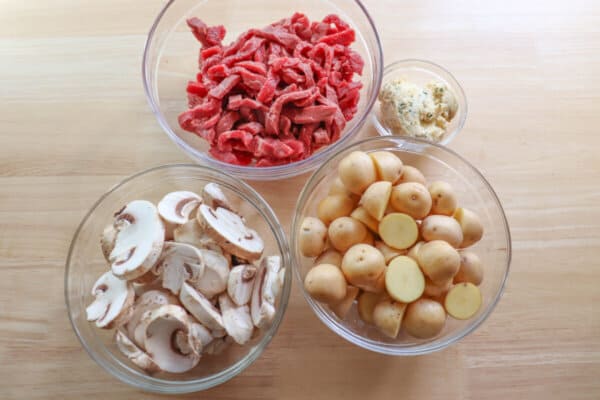 Steak and mushroom foil pack ingredients in glass bowls.
