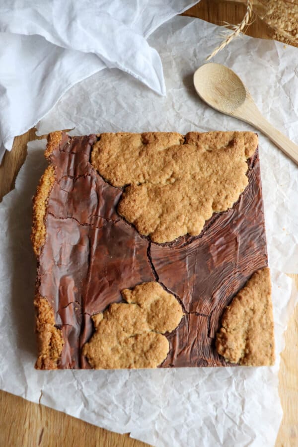 Large square of fudge and oat cookie baked on a sheet of parchment paper.
