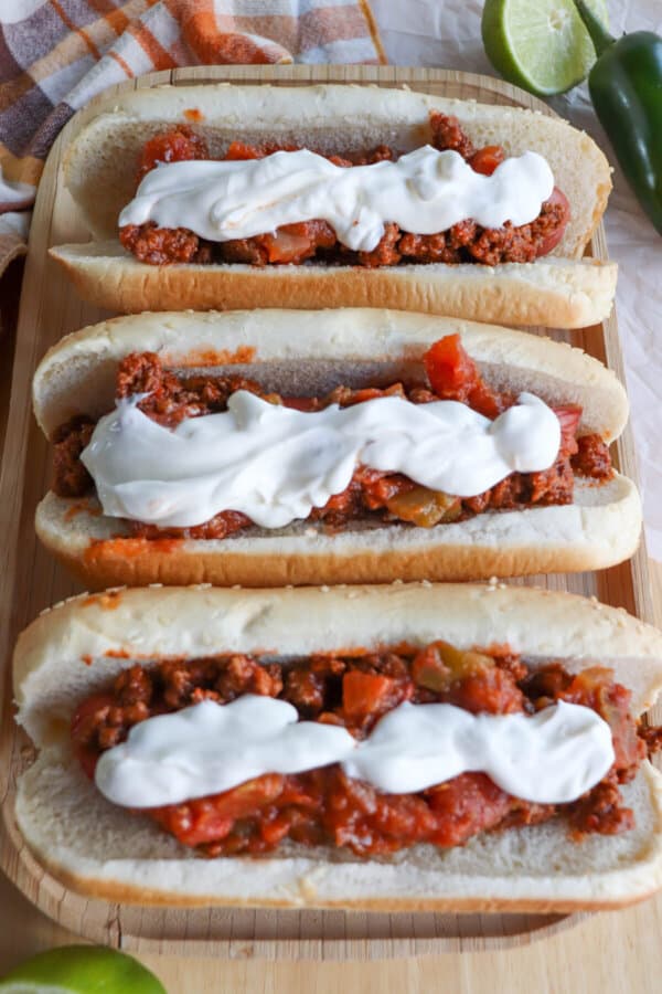 Hot dogs in buns with taco meat and sour cream topping.