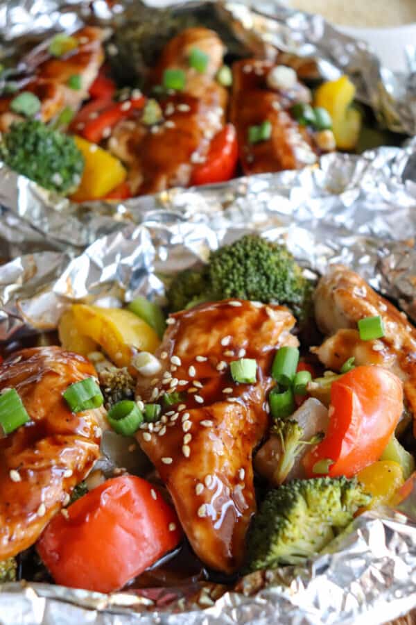 Close up of chicken and vegetables covered in teriyaki sauce in a foil packet.