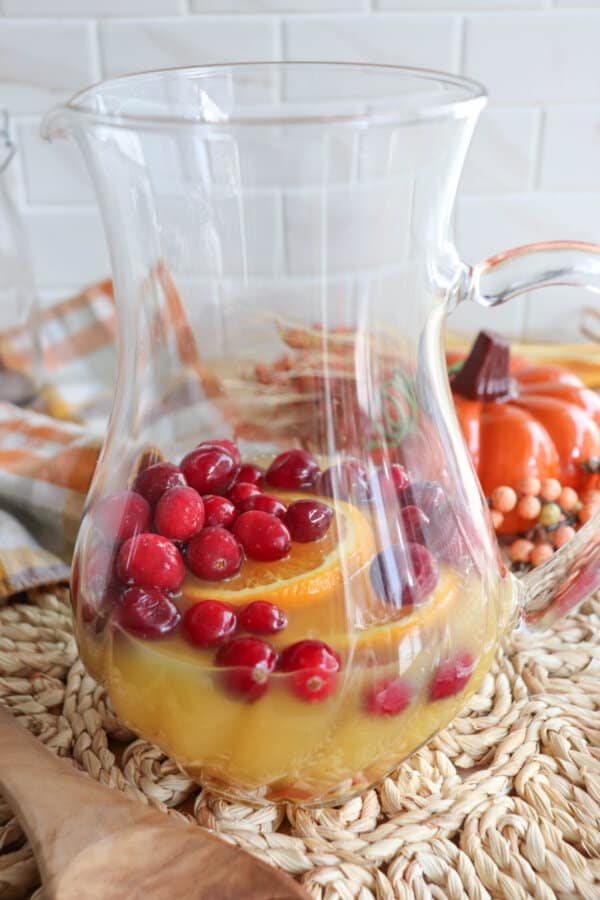 Fruit in a glass pitcher with orange juice.