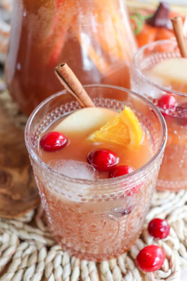 Thanksgiving punch in a decorative glass with an apple slice, orange slice and cranberries.
