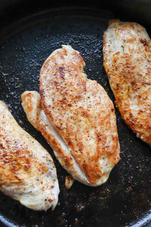 Cooked chicken breast with Italian seasoning and paprika in a cast iron skillet.