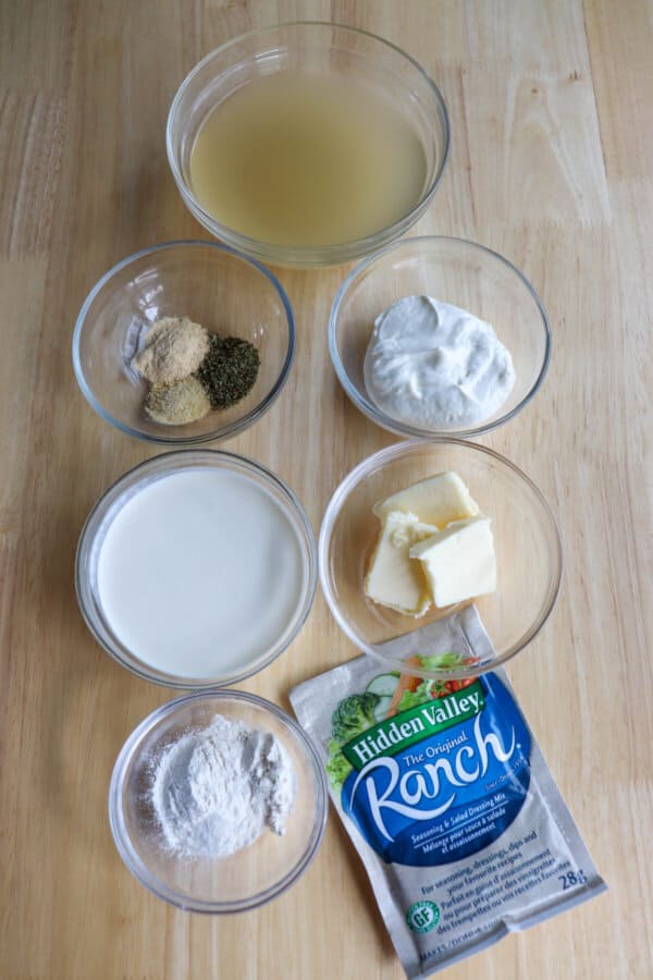 Chicken ranch ingredients in clear glass bowls on a wood surface.