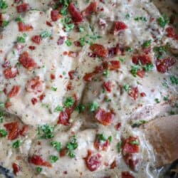 Chicken breast covered in a ranch cream sauce garnished with crisp bacon bits and parsley.