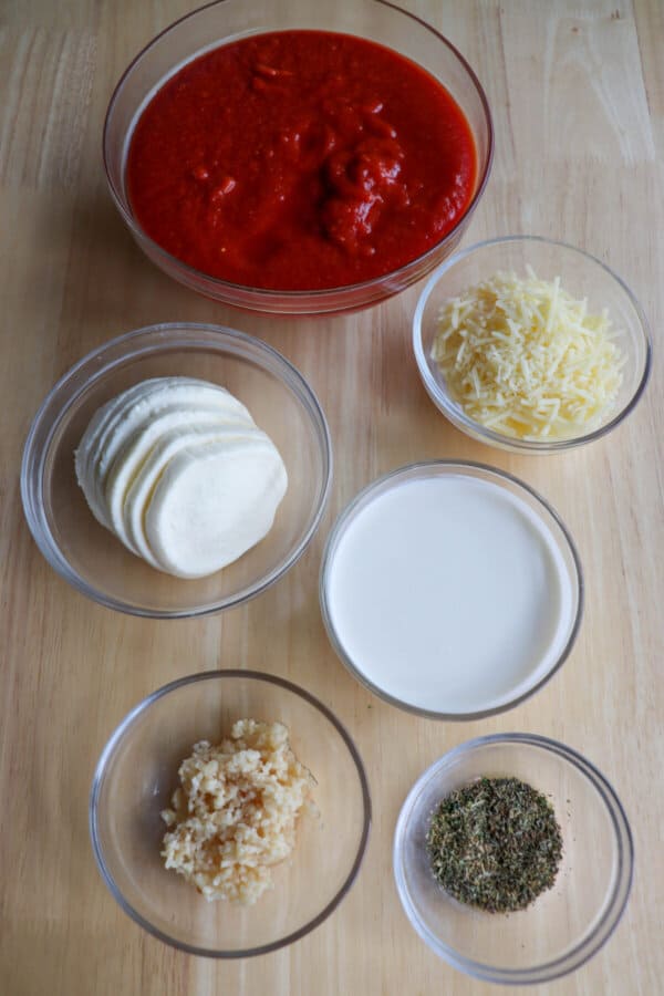 Ingredients to make tomato basil chicken in clear glass bowls.