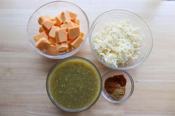 Crockpot queso ingredients in clear glass bowls.