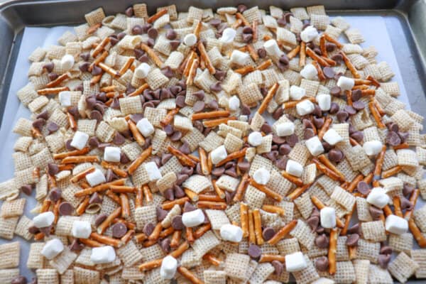 Chex, pretzels and mini marshmallows spread out on a baking sheet.